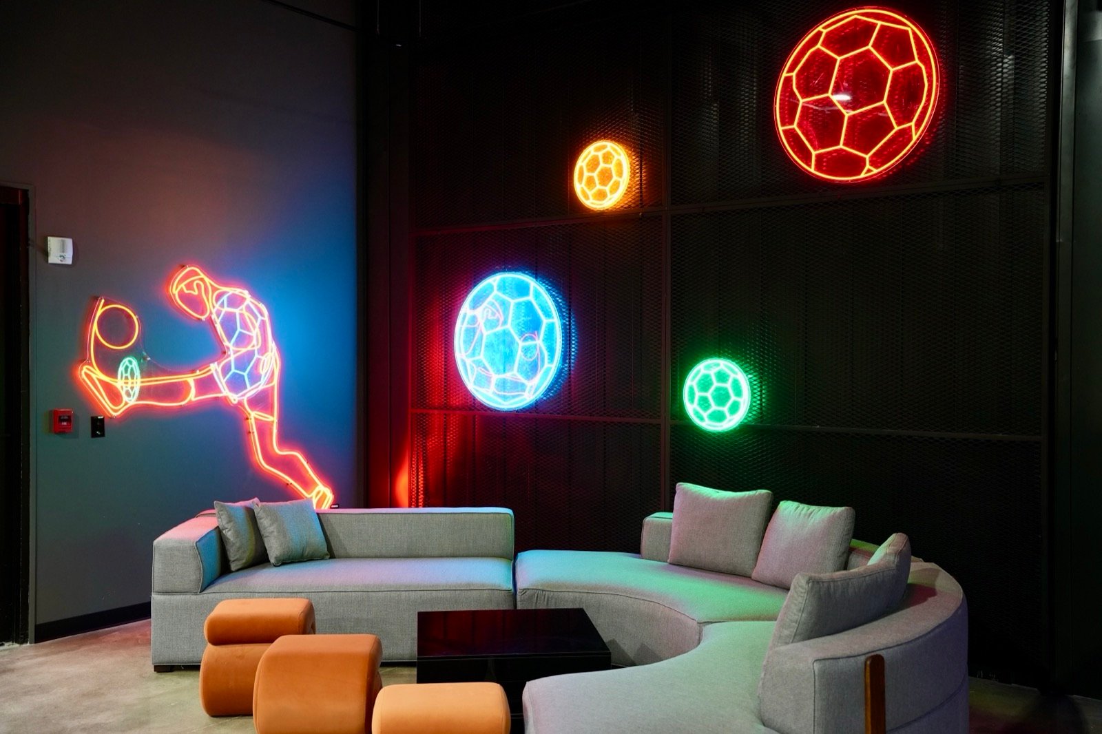 Lounge area at Just Play with neon soccer-themed wall art