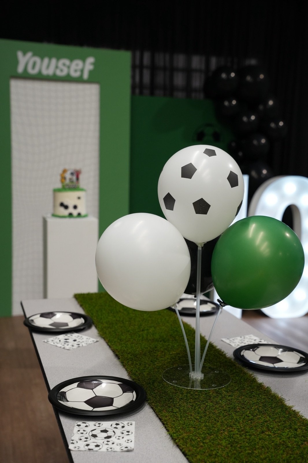 Soccer-themed birthday party table with balloons and a personalized name backdrop at Just Play