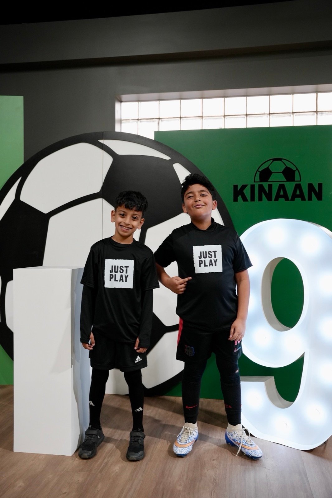 Two kids in Just Play shirts celebrating a birthday party with a light-up number sign